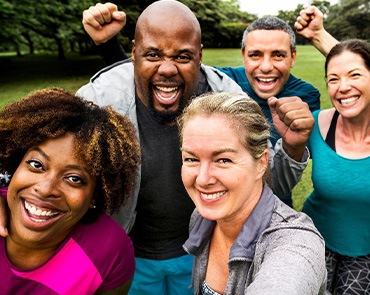Group of adults outside smiling taking selfie together