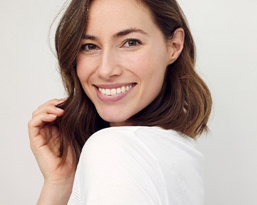 Woman with brown hair looking over shoulder smiling
