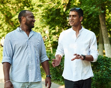 Two men outside walking and talking