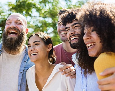 Group of people with nice teeth outside smiling together