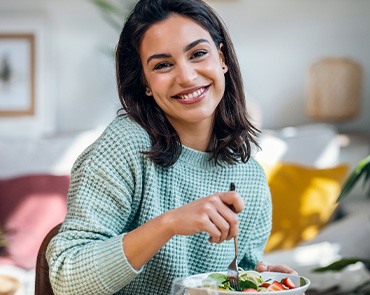 Woman in green sweater eating salad
