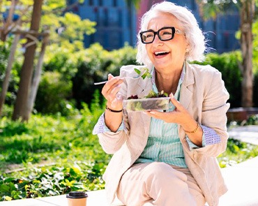Lady smiles while eating salad