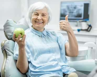 Patient holding an apple and giving a thumbs-up 